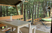 Uitzicht vanuit een Lodgetent op Camping Luna del Monte in Italië, met houten tafel en banken op terras.