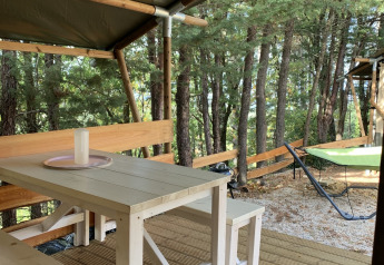 Udsigt fra Lodgetent ved Campsite Luna del Monte i Italien med træbord og bænk på terrasse i skoven.