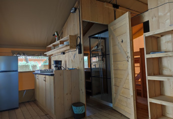 Interieur van safaritent Lodgetent op Camping Luna del Monte in Italië met houten meubels en keuken.