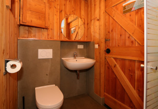 Holzbad mit Toilette, Waschbecken und Spiegel in einem Tiny House in De Wije Werelt, Niederlande.