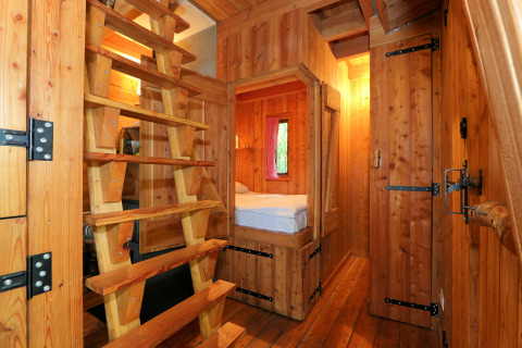 Holzinterior des Tiny House Van Gogh bei De Wije Werelt in den Niederlanden mit Bett und Leiter.