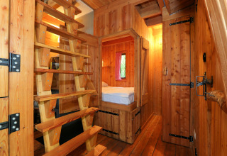 Holzinterior des Tiny House Van Gogh bei De Wije Werelt in den Niederlanden mit Bett und Leiter.