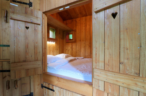 Gezellige slaapkamer in Nature Lodge bij De Wije Werelt, Nederland, met houten wanden en bed.