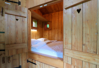 Gezellige slaapkamer in Nature Lodge bij De Wije Werelt, Nederland, met houten wanden en bed.