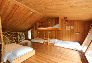 Houten slaapzaal van Nature Lodge in De Wije Werelt, Nederland, met eenpersoonsbedden en stapelbed.