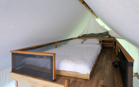 Knusse slaapruimte met bed in een glamping safaritent bij De Wije Werelt in Nederland, stijlvol ingericht.