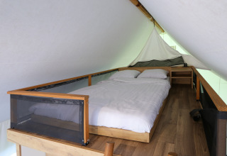 Knusse slaapruimte met bed in een glamping safaritent bij De Wije Werelt in Nederland, stijlvol ingericht.