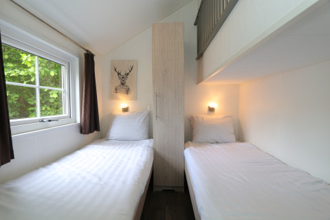 Bright Forest Lodge twin bedroom with white bedding and window view at De Wije Werelt in the Netherlands.