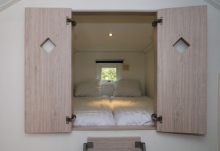 Slaapplek met open houten deuren in Forest lodge De Wije Werelt, Nederland, gezien van binnenuit.