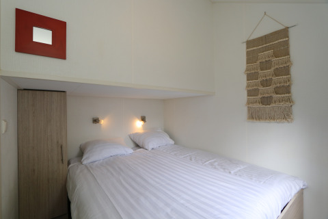 Gezellige slaapkamer in Forest Lodge, De Wije Werelt, Nederland, met tweepersoonsbed en wanddecoratie.