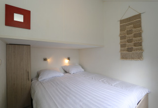 Gezellige slaapkamer in Forest Lodge, De Wije Werelt, Nederland, met tweepersoonsbed en wanddecoratie.