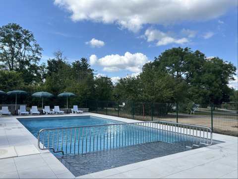 Outdoor swimming pool with lounge chairs and umbrellas at Camping Vauban, Grand Est, France on a sunny day.