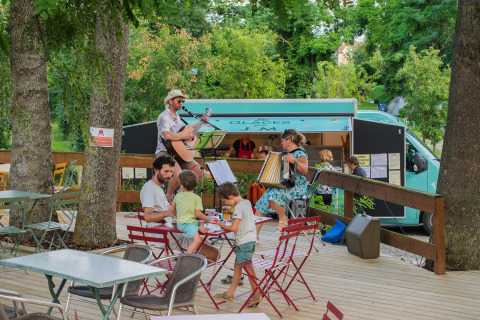 Live-Musik auf der Terrasse im Camping Vauban in Grand Est, Frankreich, mit entspannten Gästen und Foodtruck.