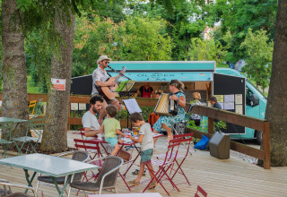 Live music performance on the terrace at Camping Vauban in Grand Est, France, with guests and a food truck.