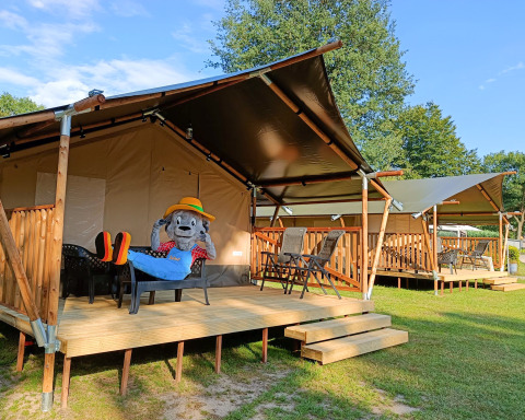 Safari-Zelte mit Holzterrasse auf dem Campingplatz De Rammelbeek, Overijssel, Niederlande, Maskottchen sitzt.