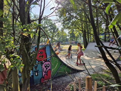 Kinder fahren Roller auf einer Skateanlage im Grünen im Ferienpark De Rammelbeek, Overijssel, Niederlande.