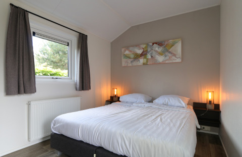 Dormitorio en la cabaña Velthorst en De Wije Werelt, Países Bajos, con cama doble, ventana y decoración moderna.
