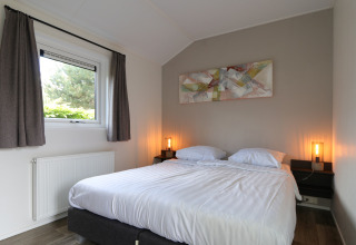 Dormitorio en la cabaña Velthorst en De Wije Werelt, Países Bajos, con cama doble, ventana y decoración moderna.