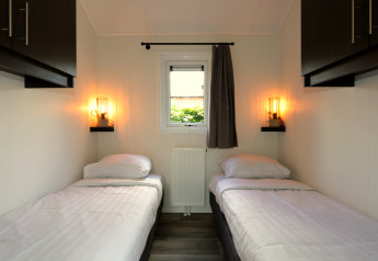 Moderne lodgekamer in Velthorst, De Wije Werelt in Nederland, met twee eenpersoonsbedden en raam.