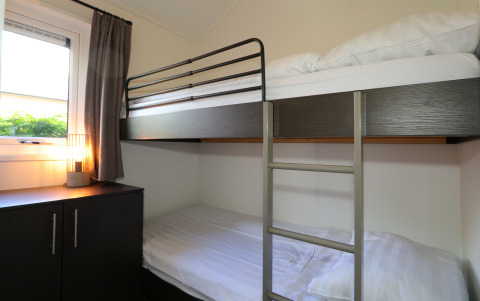 Habitación con litera, armario y lámpara en la cabaña Velthorst de De Wije Werelt, Países Bajos, luz diurna.
