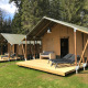 Two safari tents with wooden decks and lounge chairs, nestled in a lush forest setting.