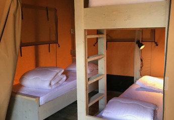 Vue intérieure d'une tente safari avec un lit superposé et un lit simple au Camping La Sténiole, France.