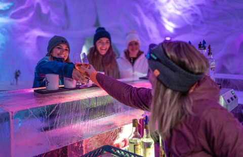 Des femmes dégustent des boissons au bar de glace d’Iglo Lodge Burgberg – Iglo Beieren, ambiance lumineuse.