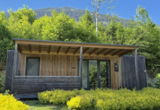 Modern glamping lodge at Seecamping Kleblach-Lind in Carinthia, surrounded by lush greenery and mountains.