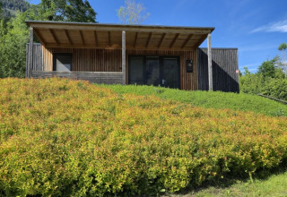 Træhytte glamping indkvartering på Seecamping Kleblach-Lind, omgivet af frodige grønne bakker og blå himmel.