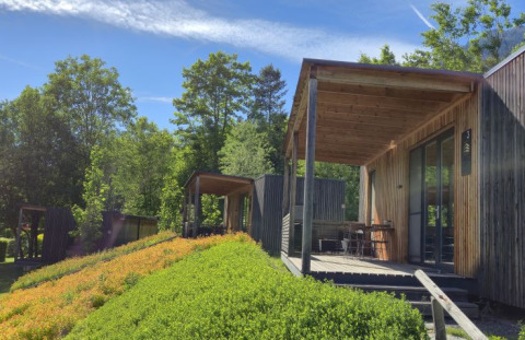Lodges en bois modernes au Seecamping Kleblach-Lind, entourés de verdure et sous un ciel bleu en Carinthie.