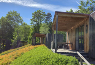 Moderne houten lodges bij Seecamping Kleblach-Lind, omgeven door groene natuur en blauwe lucht in Karinthië.