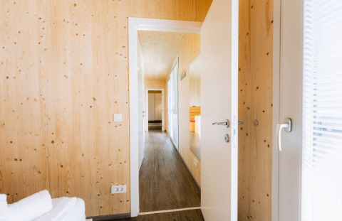 Interior luminoso de madera en lodge glamping de Seecamping Kleblach-Lind en Carintia con puerta abierta.
