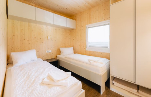 Indvendig udsigt til Seecamping Kleblach-Lind Lodge med to enkeltsenge, trævægge og moderne møbler.