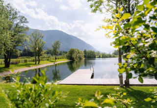 Vista panorámica del lago, muelle y montañas en Seecamping Kleblach-Lind – Lodges Karinthië glamping.