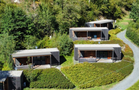 Cuatro lodges modernos de glamping rodeados de vegetación en Seecamping Kleblach-Lind, Lodges Karinthië, Austria.