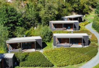 Cuatro lodges modernos de glamping rodeados de vegetación en Seecamping Kleblach-Lind, Lodges Karinthië, Austria.
