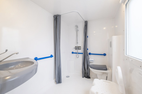 Baño accesible en Mobile home Comfort MIVA en Seasonova Camping Le Plan d’Eau, Francia, con barras de apoyo.