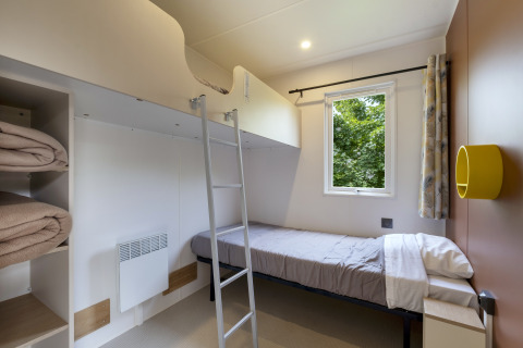 Chambre moderne avec lits superposés, fenêtre, échelle et étagères au Camping Le Plan d’Eau, Mobile home MIVA.