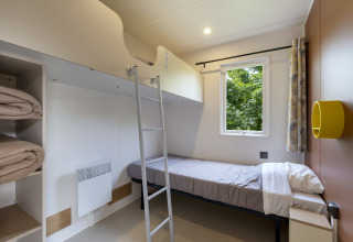 Habitación moderna con literas, ventana, escalera y estantes en Camping Le Plan d’Eau, Mobile home Comfort MIVA.