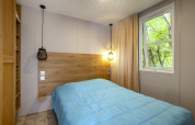 Moderne slaapkamer in Mobile home Confort bij Seasonova Camping Le Plan d’Eau, Frankrijk, met raam en bed.