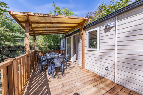 Überdachte Holzterrasse mit Essbereich an einem Static Caravan Comfort mit Klimaanlage im Grünen.