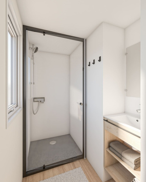 Baño moderno en caravana en Seasonova Camping Le Plan d’Eau, Francia, con ducha y lavabo visibles claramente.