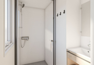 Baño moderno en caravana en Seasonova Camping Le Plan d’Eau, Francia, con ducha y lavabo visibles claramente.