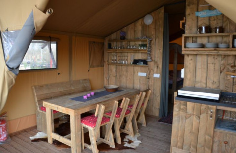 Innenansicht einer Glamping-Unterkunft mit Holzmöbeln und Essecke bei Inselcamping Kollersee – Safaritenten Rheinland-Pfalz.