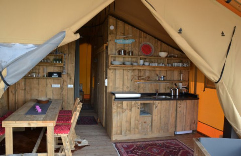 Interieur van een safaritent bij Inselcamping Kollersee met houten meubels en eethoek.