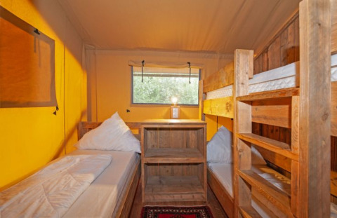 Interieur van een safaritent bij Inselcamping Kollersee met houten stapelbedden en een gezellige sfeer.