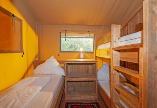 Indretning af safaritelt på Inselcamping Kollersee med køjesenge og lyst træinteriør i campingstil.
