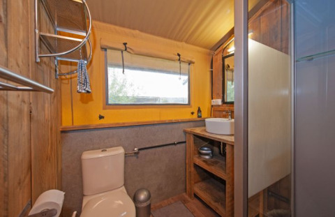 Baño en tienda safari glamping en Inselcamping Kollersee, Renania-Palatinado, con inodoro y ducha.