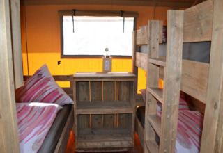 Vue intérieure d’une tente safari glamping à Inselcamping Kollersee avec lits superposés et meubles en bois.