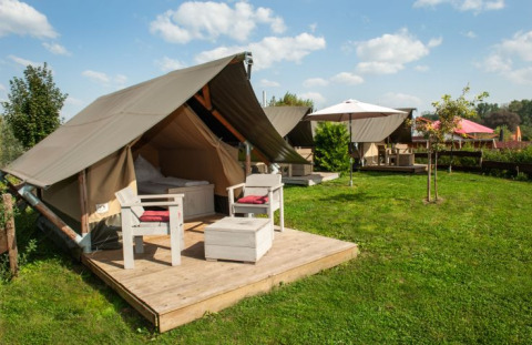 Glamping en Inselcamping Kollersee con tiendas safari en Renania-Palatinado, terraza de madera y césped verde.